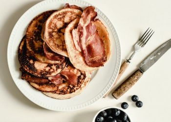 blueberries and a plate of pancakes with bacon
