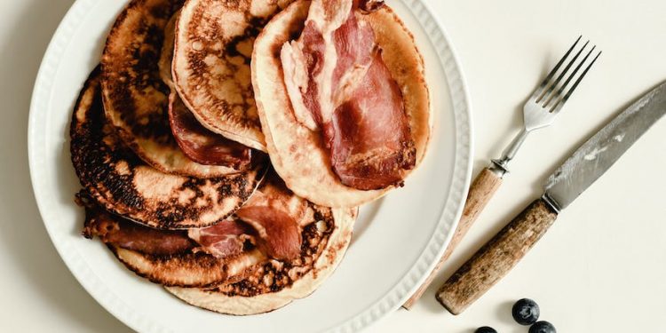 blueberries and a plate of pancakes with bacon